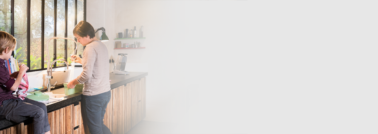 Женщина моет посуду горячей водой